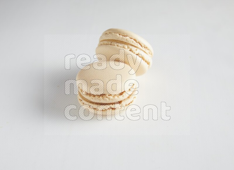 45º Shot of two White Caramel fleur de sel macarons on white background