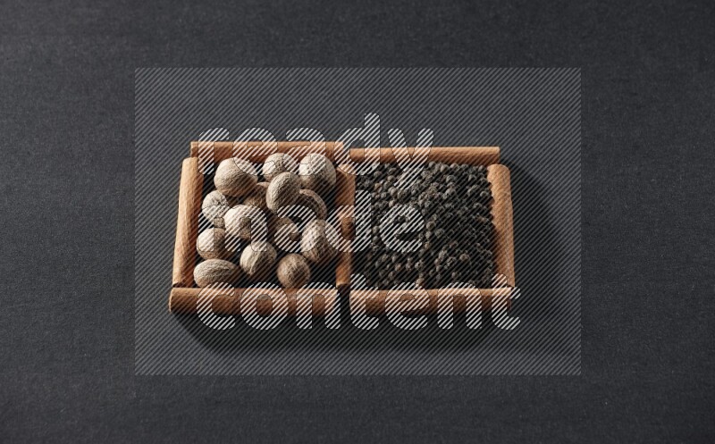 2 squares of cinnamon sticks full of nutmegs and black peppers on black flooring