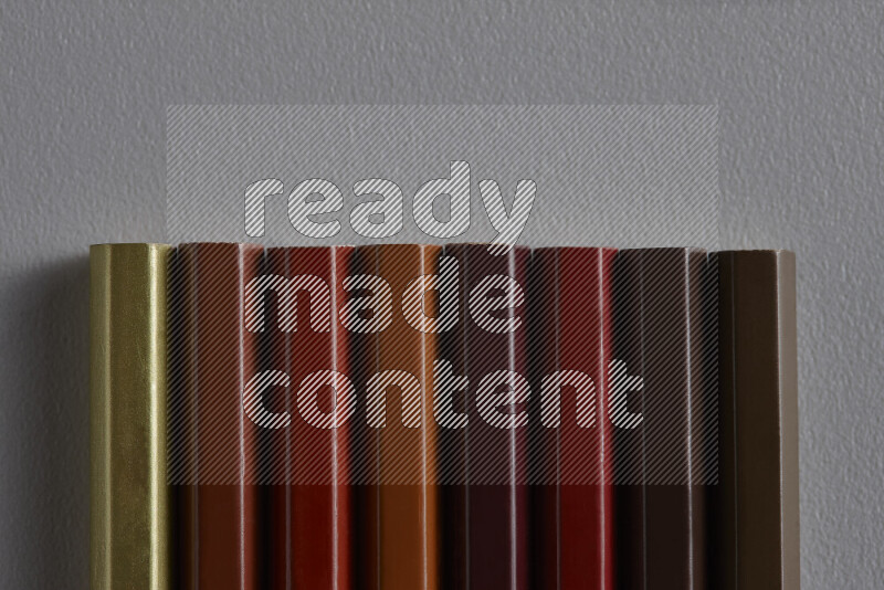 مجموعة من أقلام الرصاص الملونة مرتبة لتعرض تدرجا من الألوان البنية علي خلفية رمادية