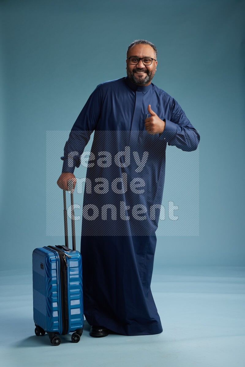 Saudi Man without shimag Standing pulling travel bag on blue background