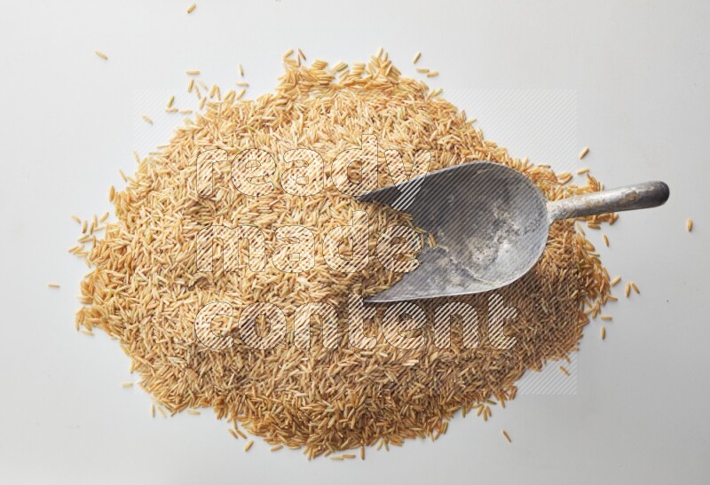 Top-view of a long grain brown rice, and shovel on white background