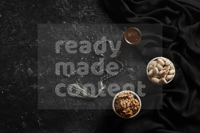 مكسرات في أطباق فخارية مع القهوة علي خلفية سوداء خشبية