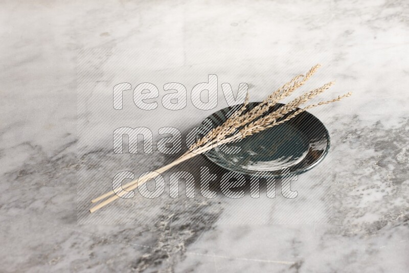 Wheat stalks on multicolored pottery plate on grey marble background