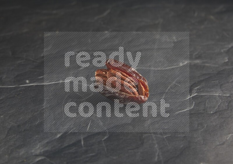 pecan stuffed madjoul date on a black textured background