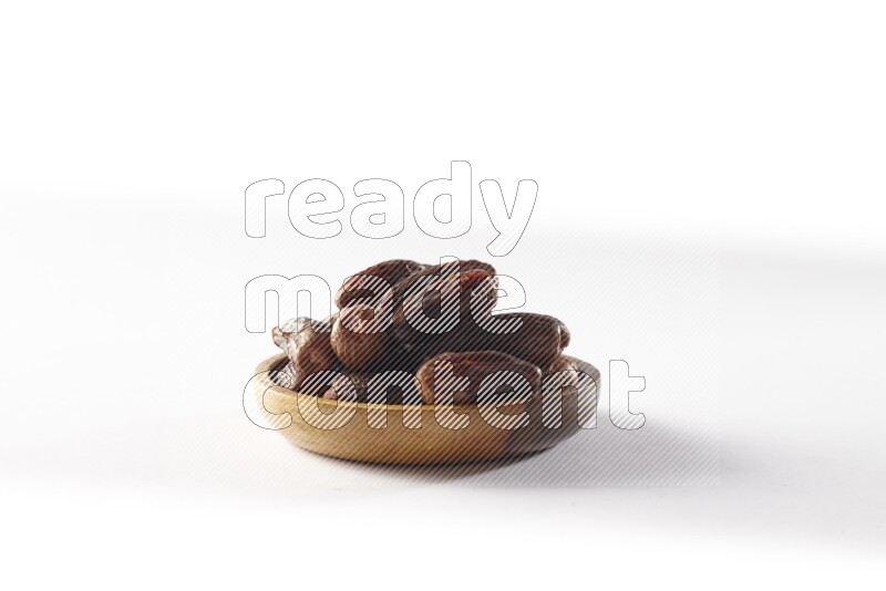 Dates in a wooden bowl on white background