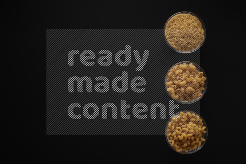 Different pasta types in 3 glass bowls on black background