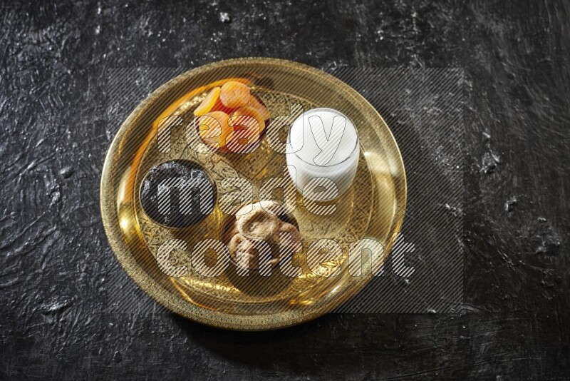 Dried fruits in metal bowls with sobya on a tray in dark setup