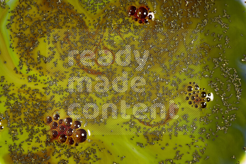 A close-up of sparkling gold glitter scattered on swirling green and red background