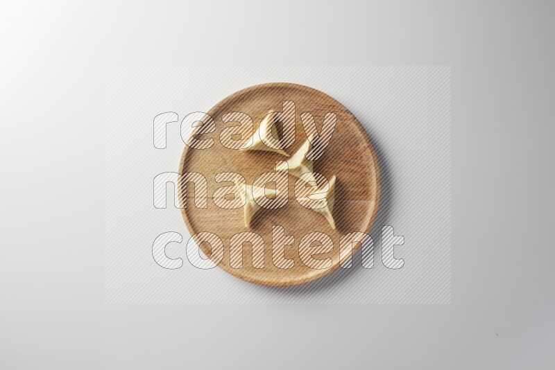 Four Sambosas on a wooden round plate on a white background