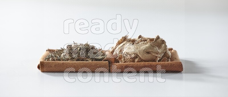 2 squares of cinnamon sticks full of dried ginger and dried basil on white flooring