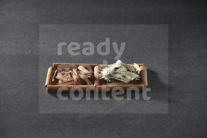 2 squares of cinnamon sticks full of cinnamon and bay laurel leaves on black flooring