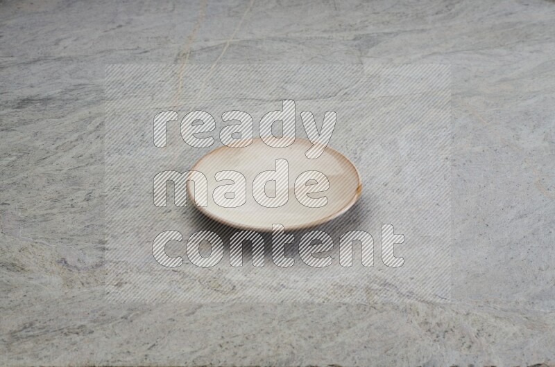 A beige pottery plate on grey marble background