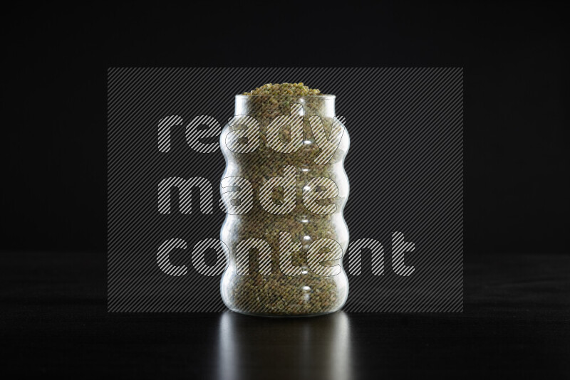 Freekeh in a glass jar on black background