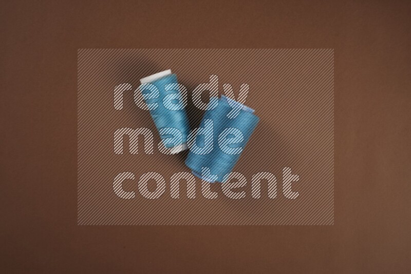 A blue collection of sewing and tailoring tools arranged on a brown background