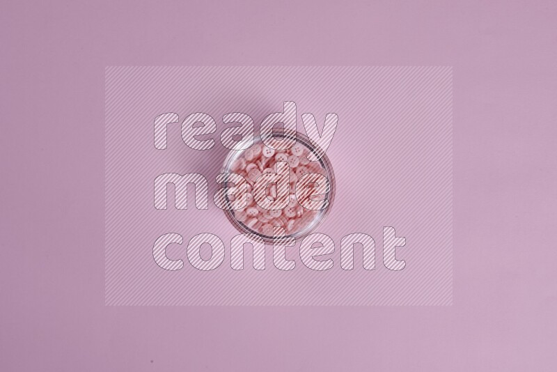 Pink buttons in a glass bowl on pink background
