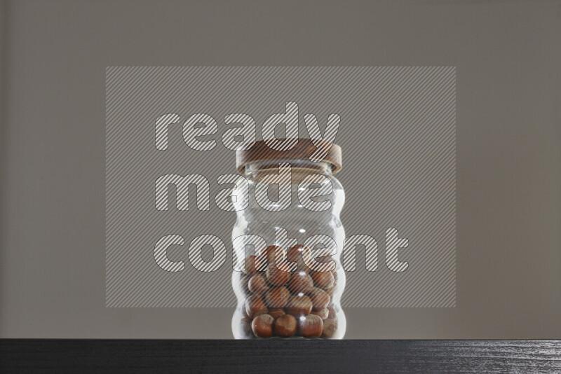 Hazelnuts in a glass jar on black background