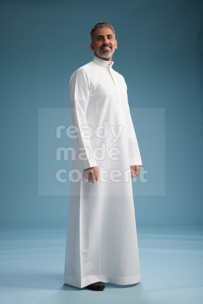 Saudi man waring thob posing to the camera on blue background