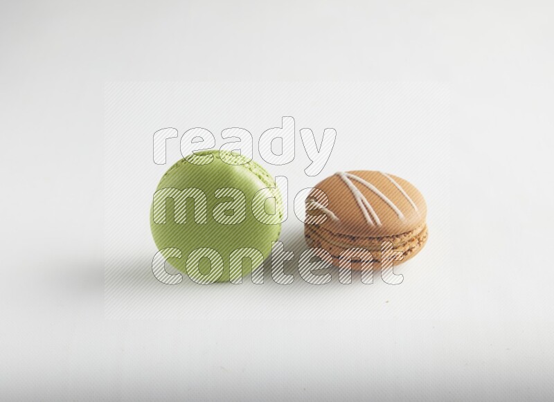 45º Shot of of two assorted Brown Irish Cream, and Green Pistachio macarons on white background