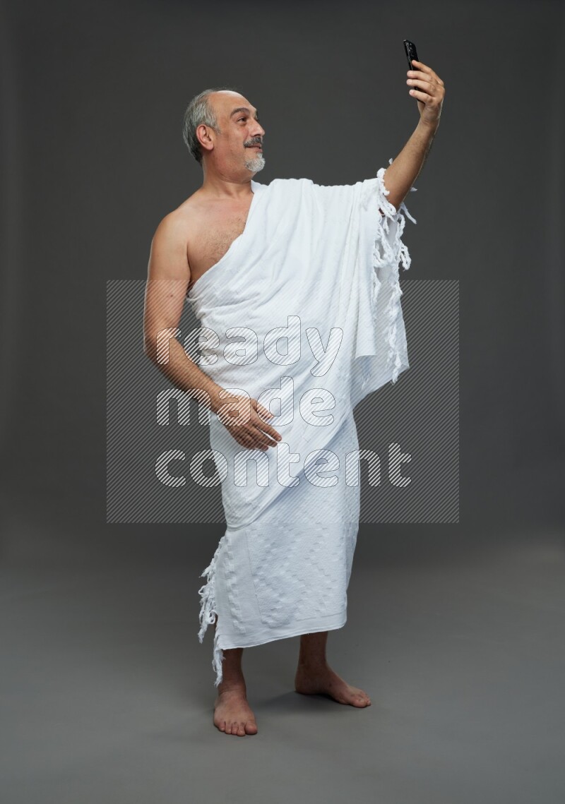 A man wearing Ehram Standing taking selfie on gray background