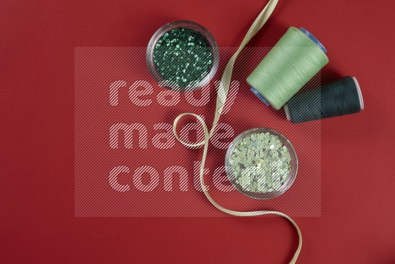 مجموعة من أدوات الخياطة والتفصيل خضراء وحمراء اللون على خلفية حمراء