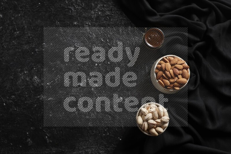 مكسرات في أطباق فخارية مع القهوة علي خلفية سوداء خشبية