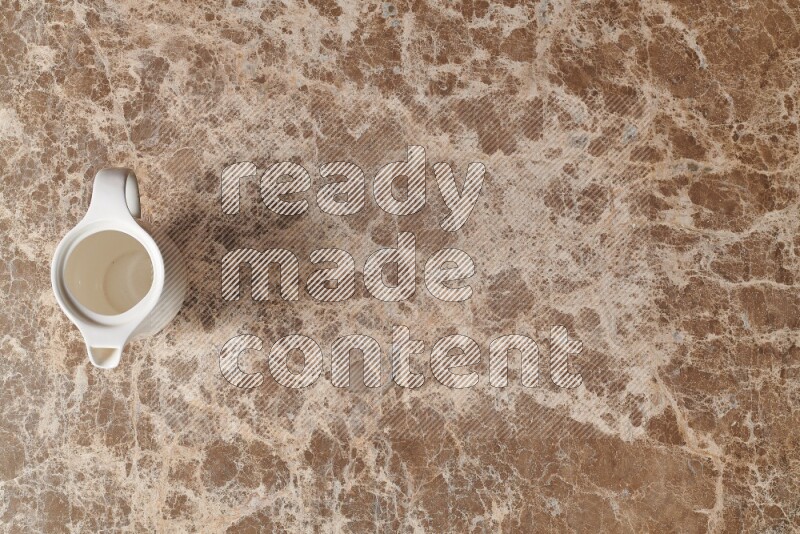 A ceramic milk jug on beige marble background