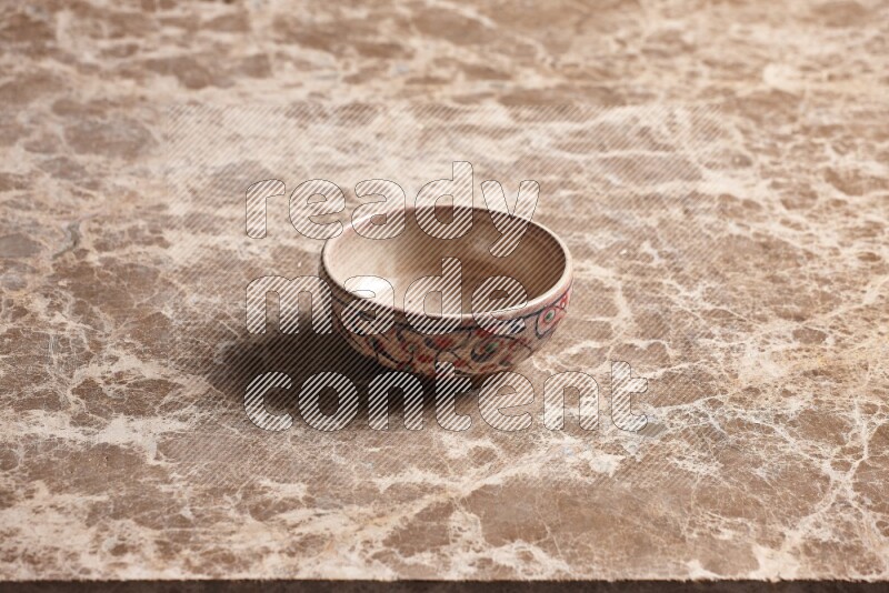 A decorative pottery bowl on beige marble background