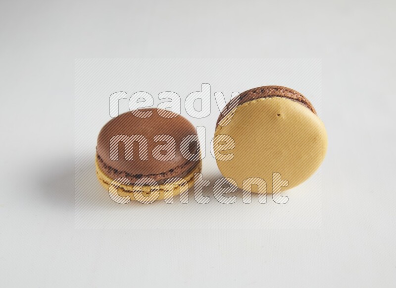 45º Shot of two Yellow and Brown Chai Latte macarons on white background