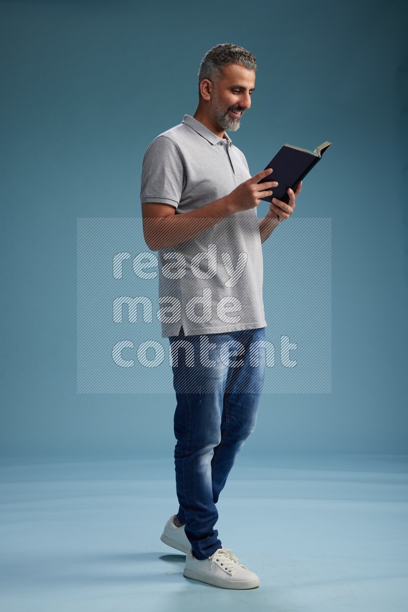 Man Standing reading book on blue background