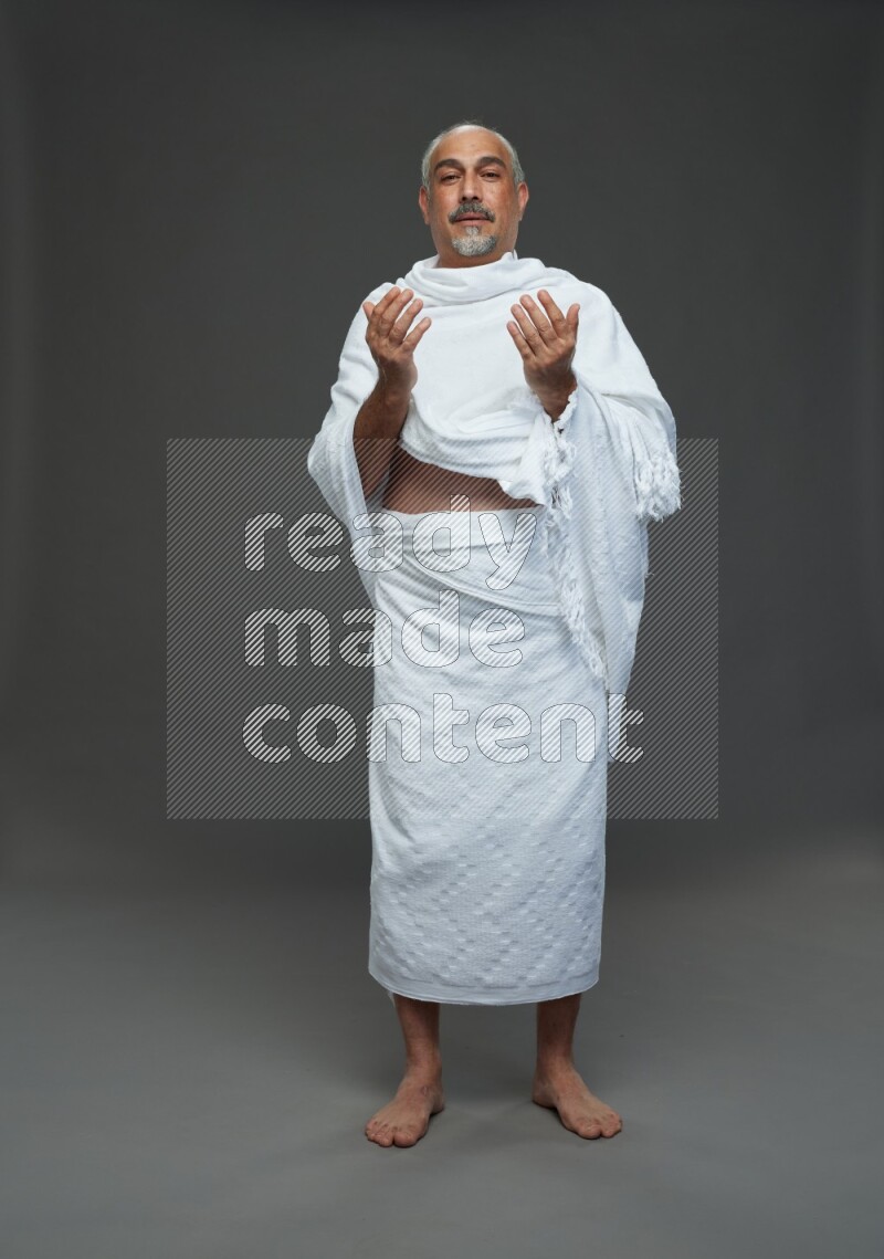 A man wearing Ehram Standing dua'a on gray background