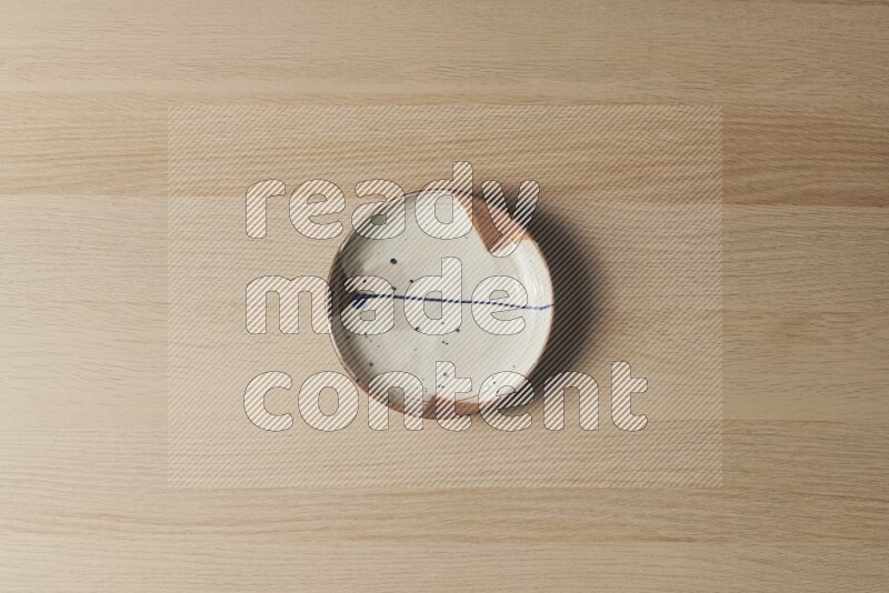 A multicolored pottery plate on light wooden background