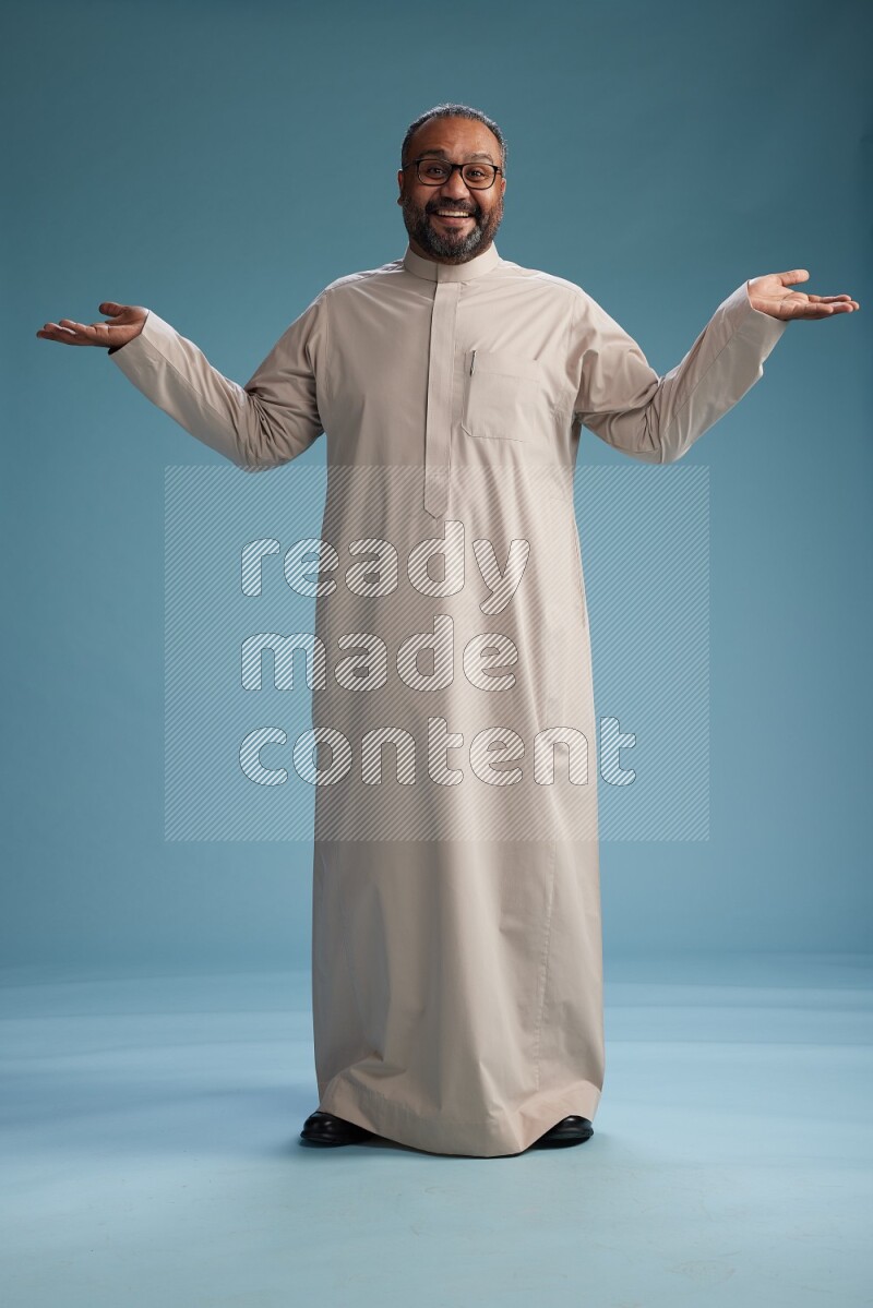 Saudi Man without shimag Standing Interacting with the camera on blue background