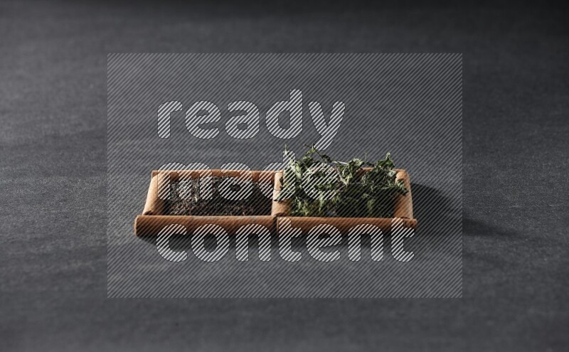 2 squares of cinnamon sticks full of tea and dried mint leaves on black flooring