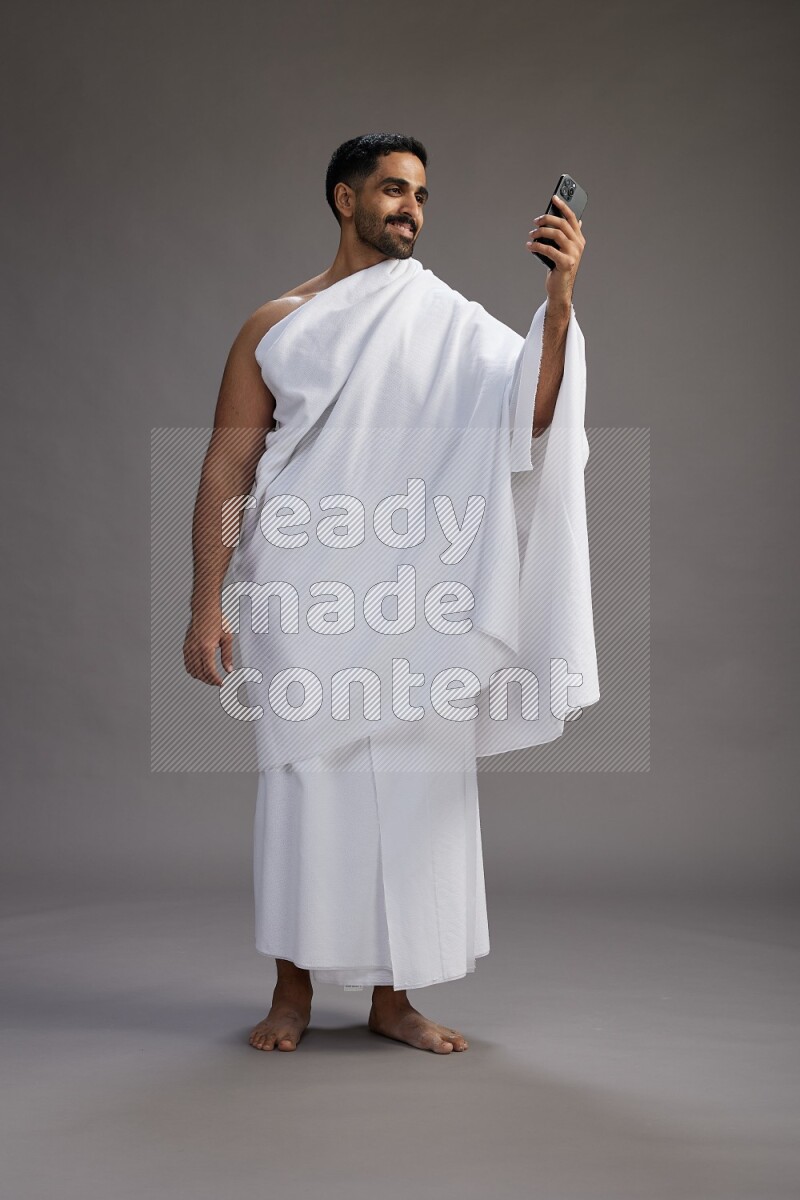 A man wearing Ehram Standing taking selfie on gray background