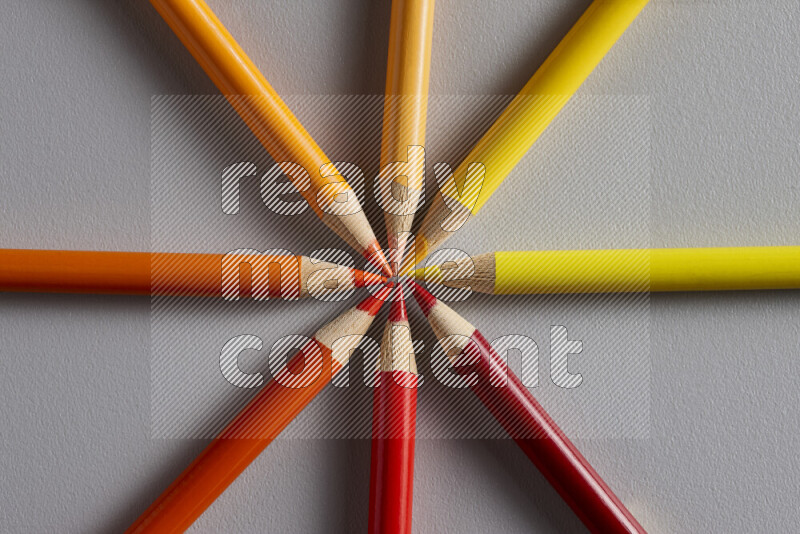 An arrangement of colored pencils in different colors on grey background