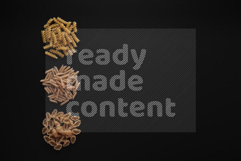 Different pasta types in 3 bunches on black background
