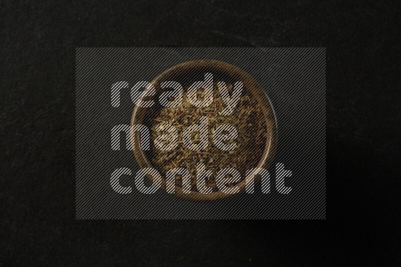 wooden round sauce bowl filled with herbs on grey textured countertop