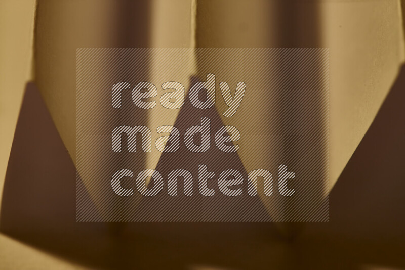 صورة مجردة مقربة تظهر طيات ورقية هندسية حادة بتدرجات الوان دافئة