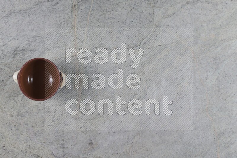 إناء فخاري متعدد الألوان مع غطائه على خلفية من الرخام الرمادي