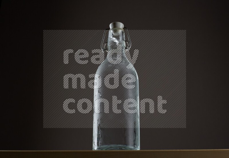 Low angle shot of a bottle of water and ice on grey background