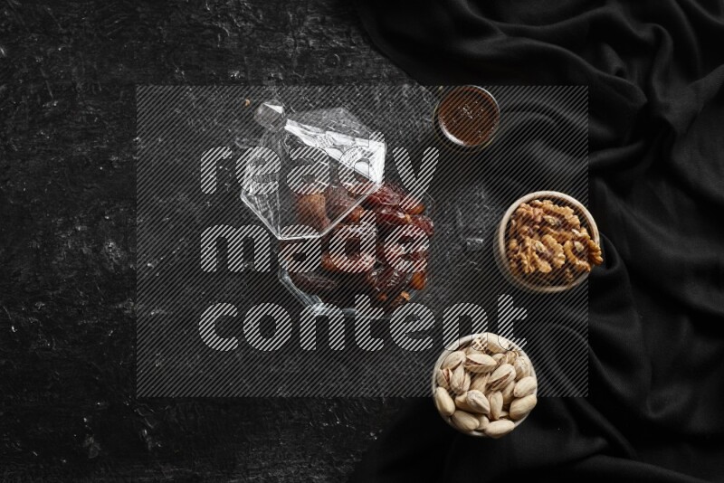 Dates in glass bowl with coffee and nuts in a dark setup