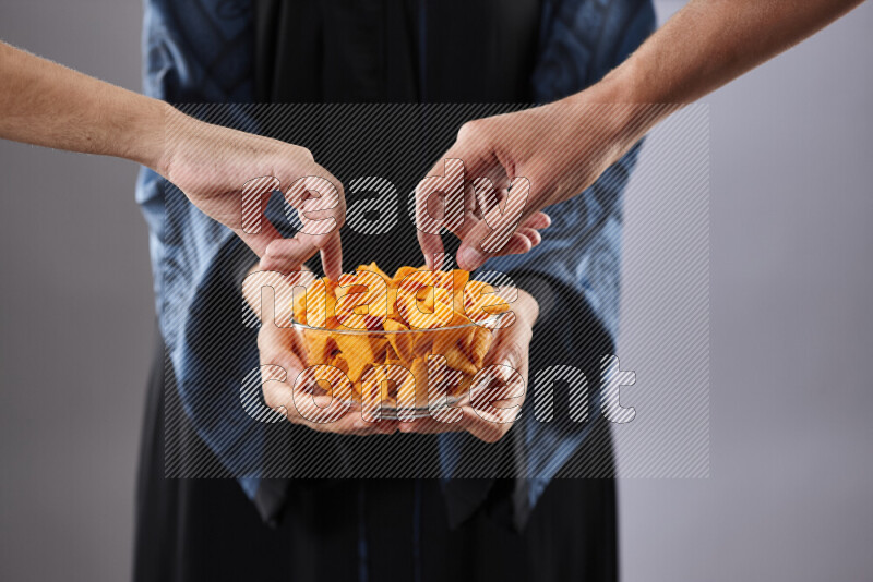 Woman in abaya holding different kinds of snacks in different positions