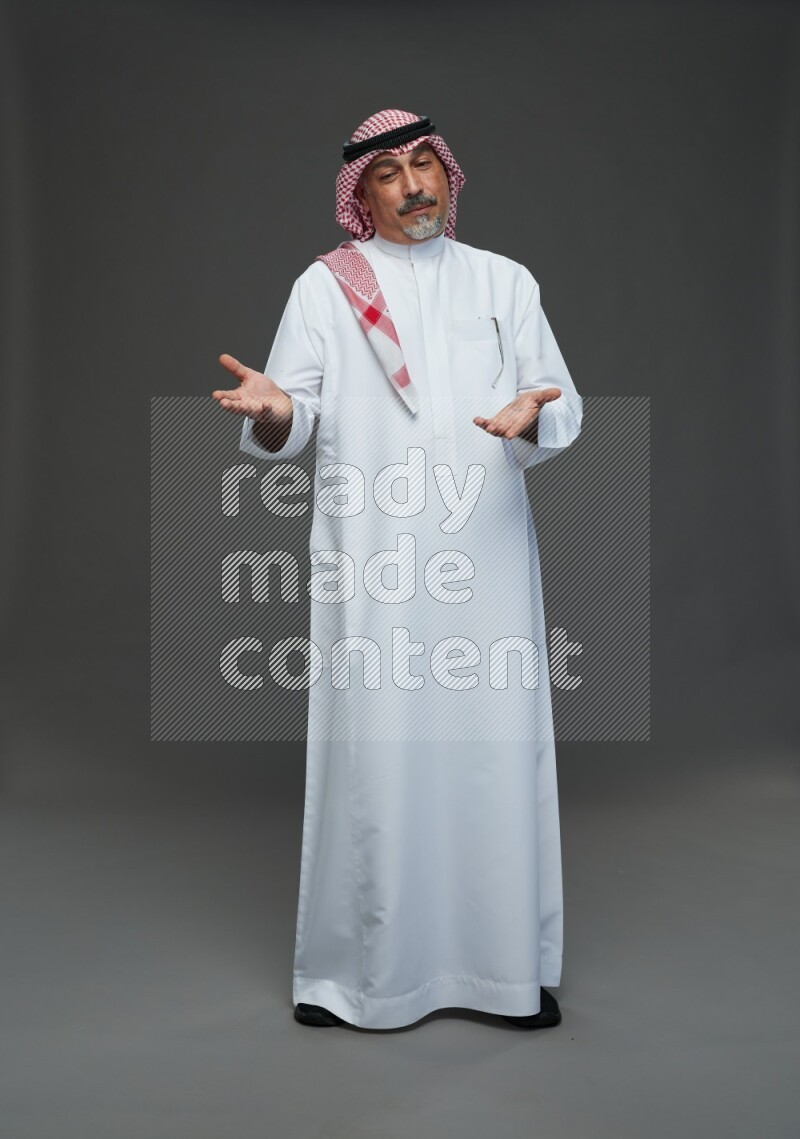 Saudi man with shomag Standing Interacting with the camera on gray background