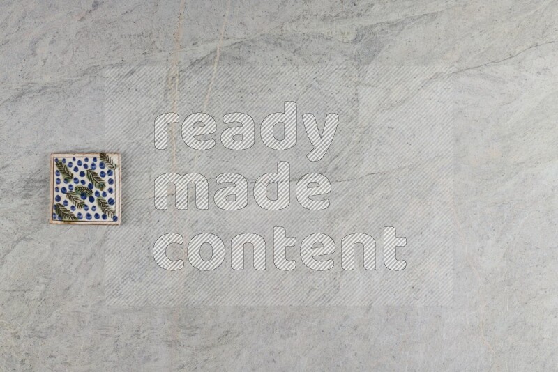 A decorative pottery coaster on grey marble background