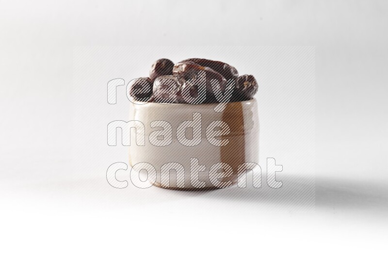 Dates in a beige pottery bowl on white background