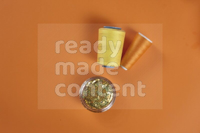 A yellow collection of sewing and tailoring tools arranged on a orange background