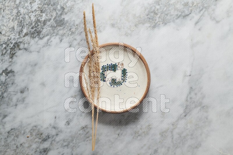 Wheat stalks on decorative pottery plate on grey marble background