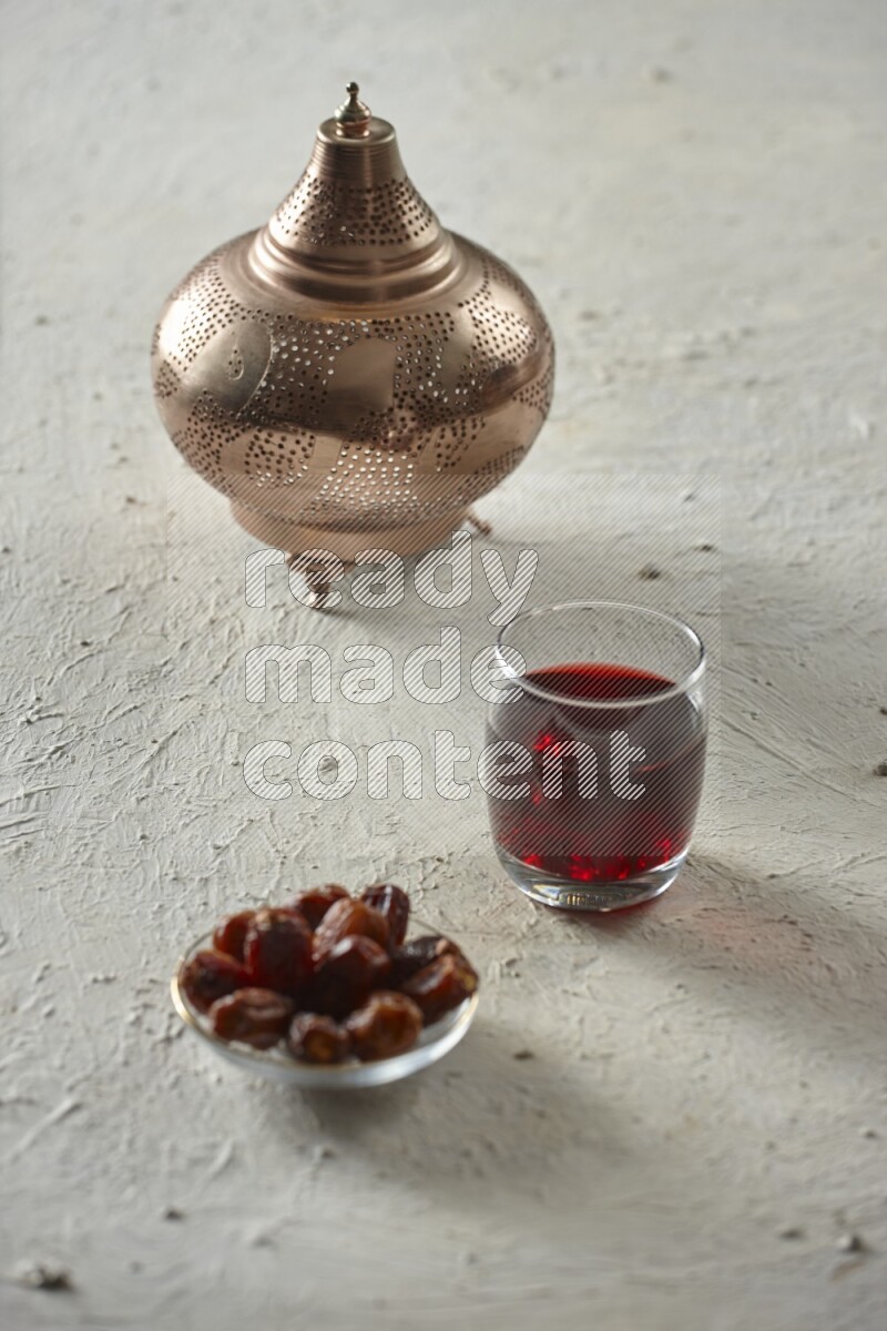 A golden lantern with different drinks, dates, nuts, prayer beads and quran on textured white background