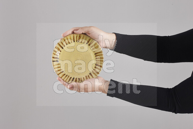 A woman in black abaya holding different pottery essentials in different positions