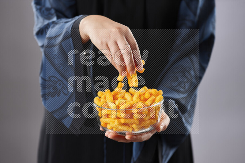 Woman in abaya holding different kinds of snacks in different positions